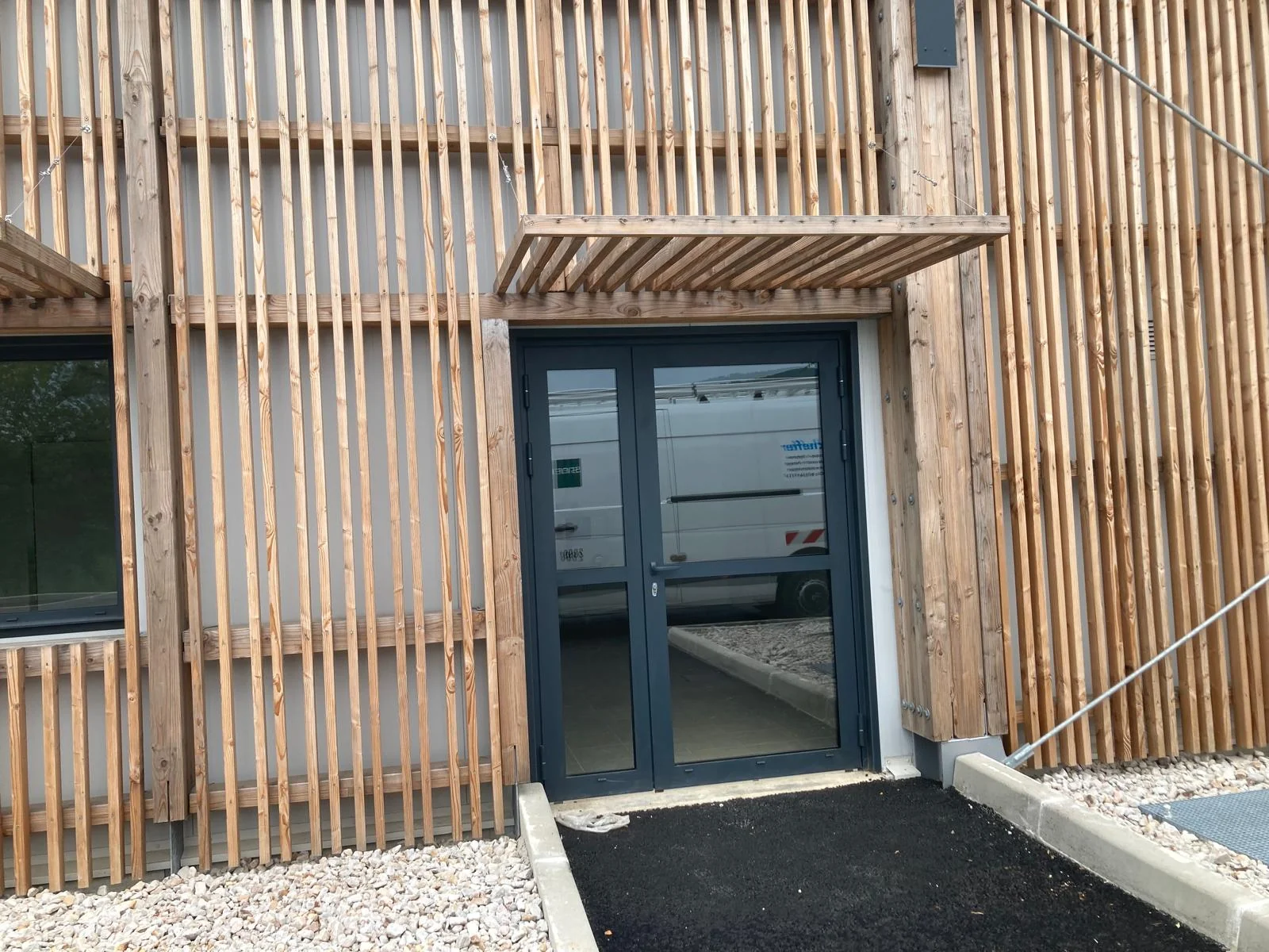 Porte d'entrée aluminium vitrée sur façade bardage bois — Wineo France